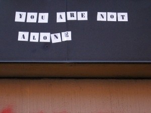 "You are not alone" typed in letters on sheets on paper taped to blackboard