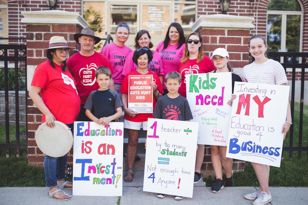 Teachers, parents, students and children holding rally signs