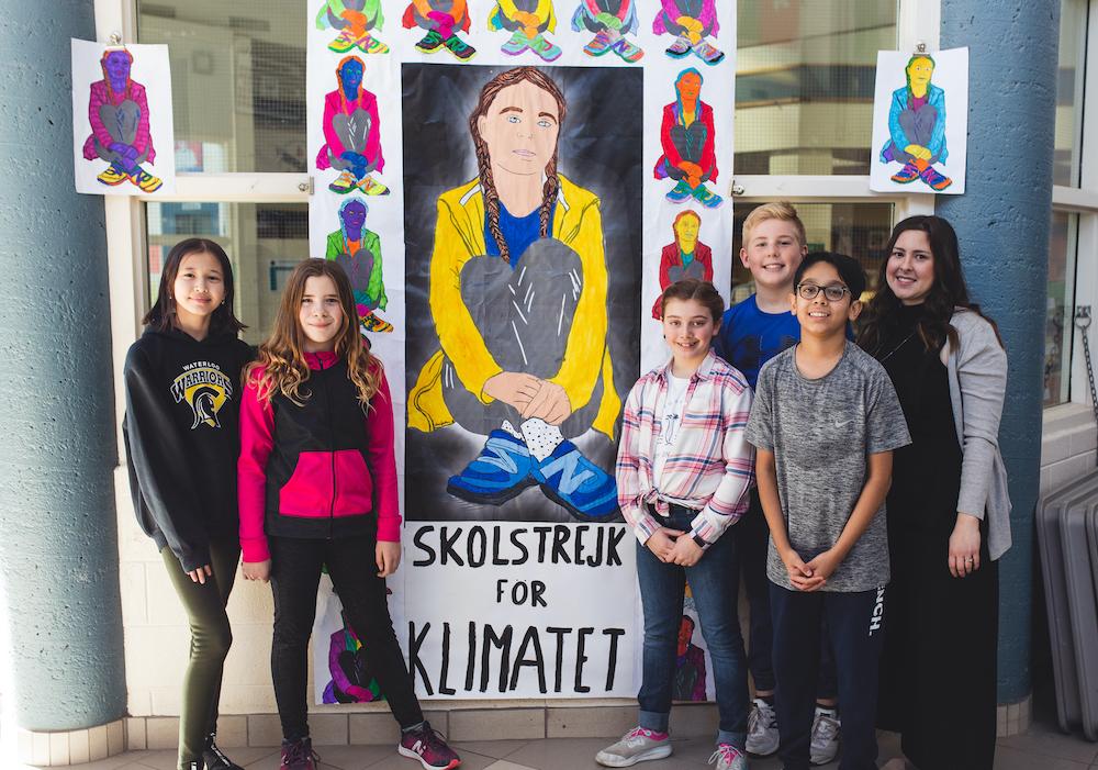 class and teacher standing in front of artwork