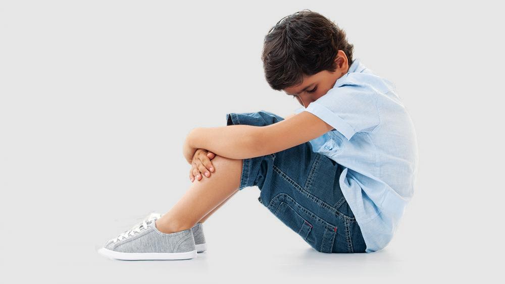 young boy sitting with head in lap