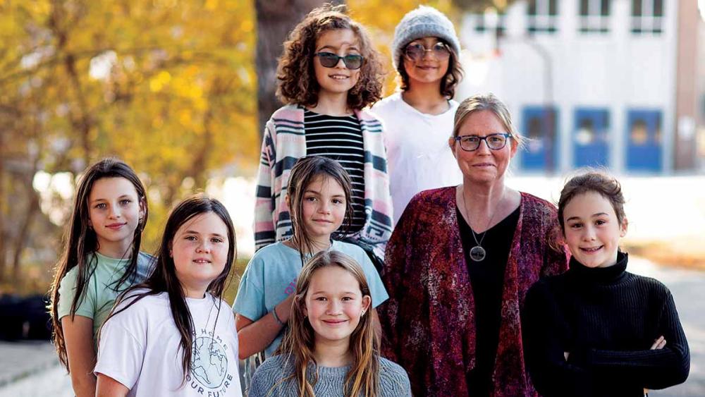 Teacher and girls standing in front of school