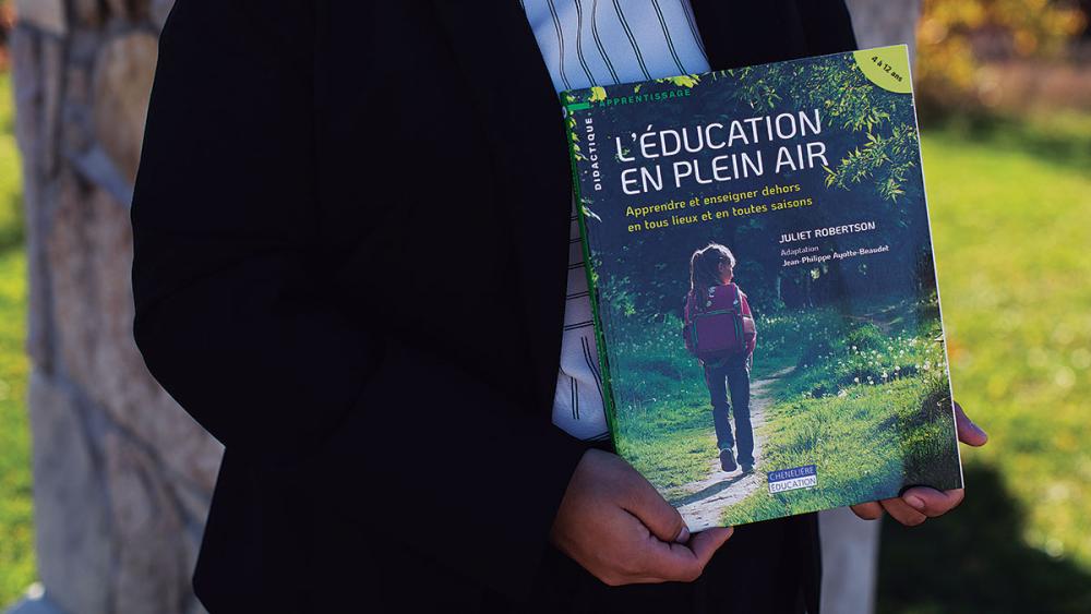Asha Nagpal posing with book L'education en plein air