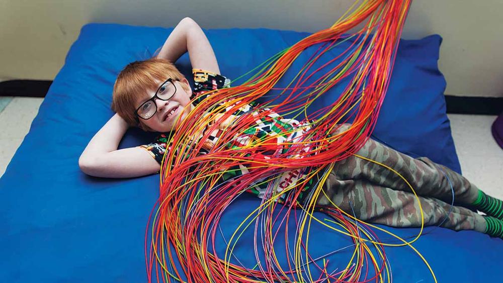 Student sitting on blue mat covered in the cables