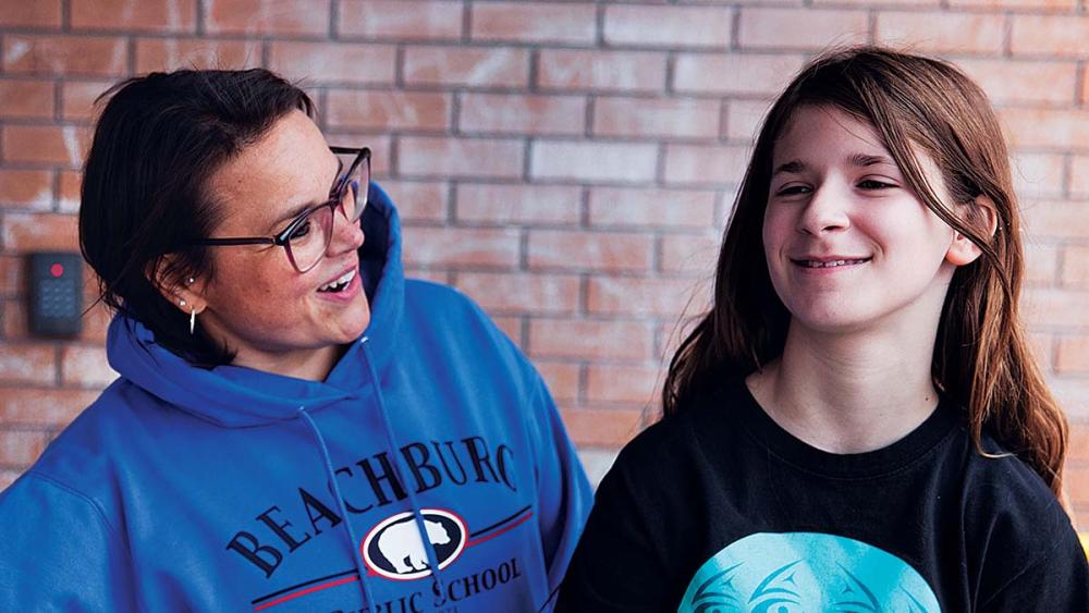 Nancy Campbell smiling with student in school