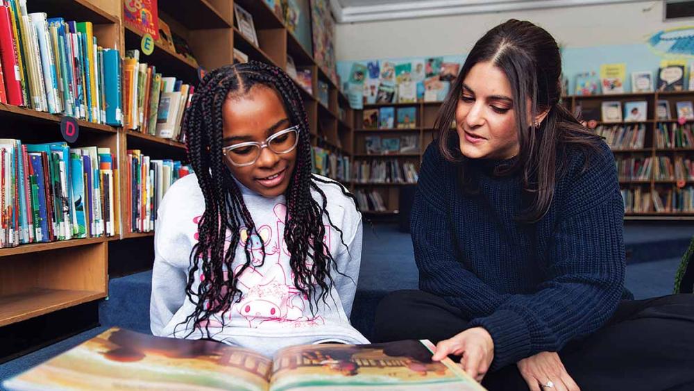 Leanna Bornstein reading with student in library