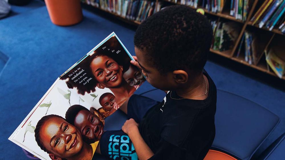 Black male student reading book in the library