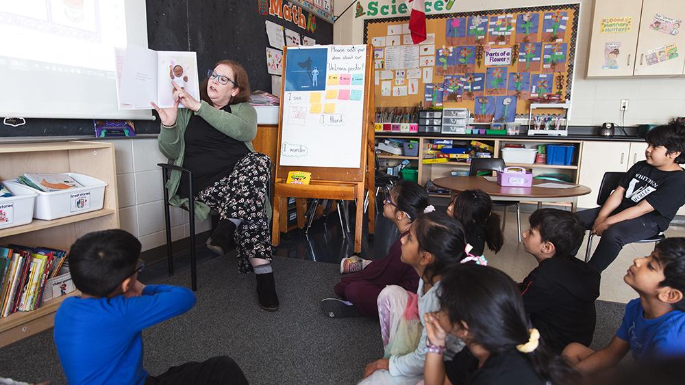 Heather Thompson reading a book in front of classroom