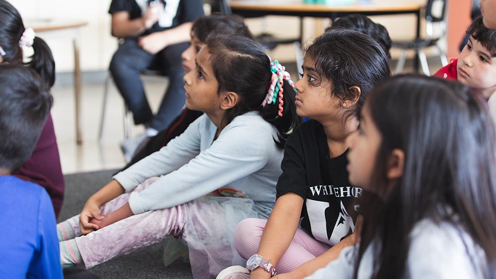 Students listening intently to Heather Thompson as she reads a book in her classroom