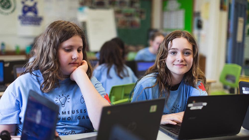Two girls in classroom using a laptop