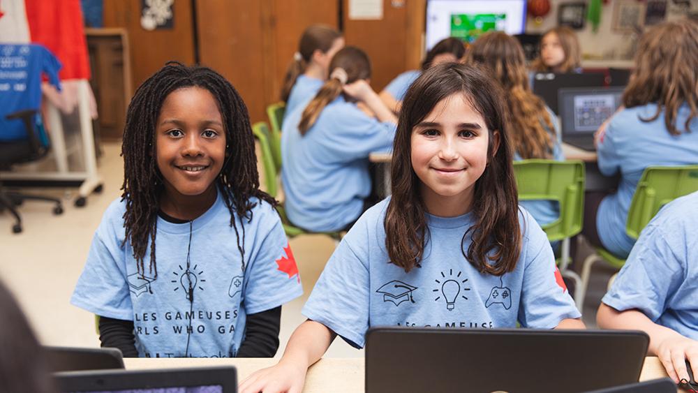 Two girls in classroom using a laptop