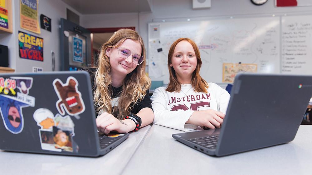 Two students working on their laptops in the classroom