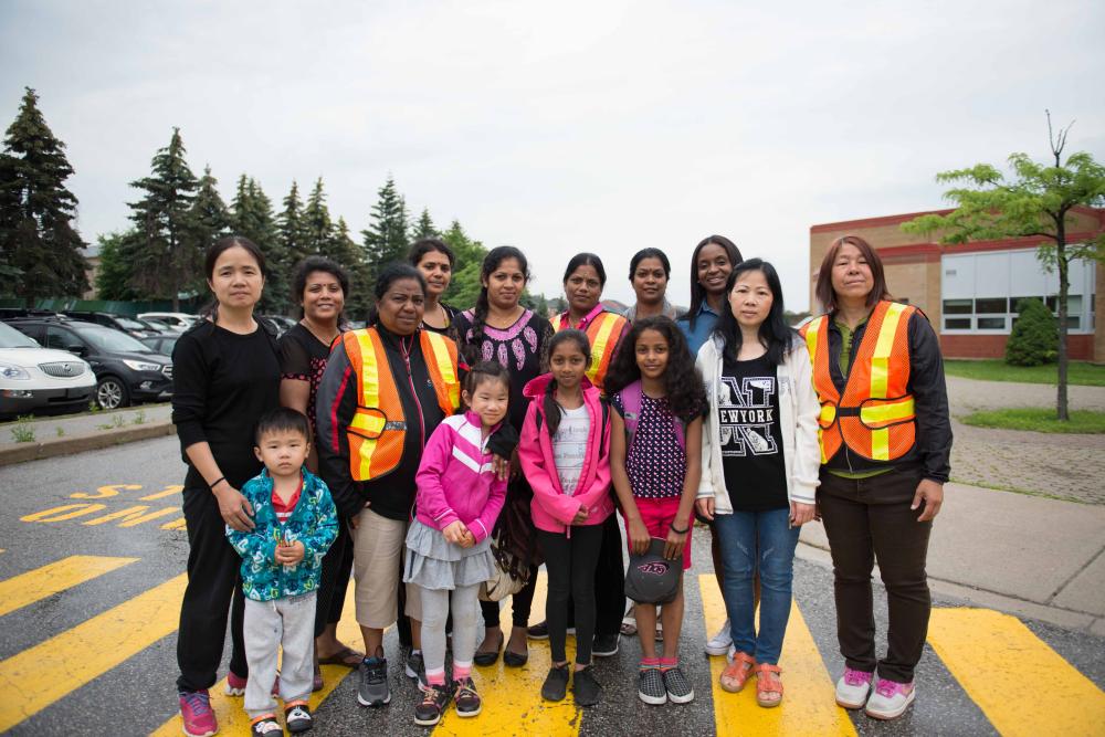 Writer Charmain Brown with students and parent volunteers standing in front of a school