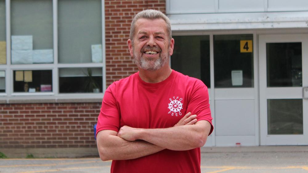 Sam Hammond posing outside of school in red ETFO t-shirt