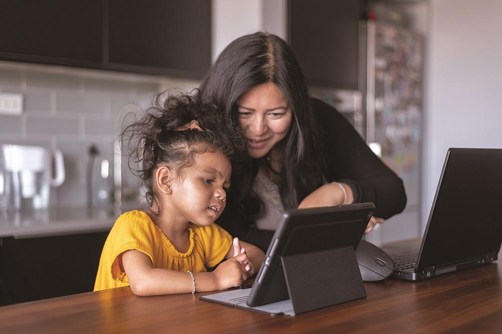 Parent showing child how to use laptop