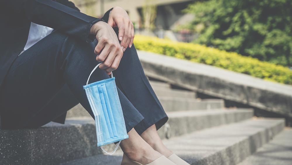 Woman sitting on steps holding medical mask