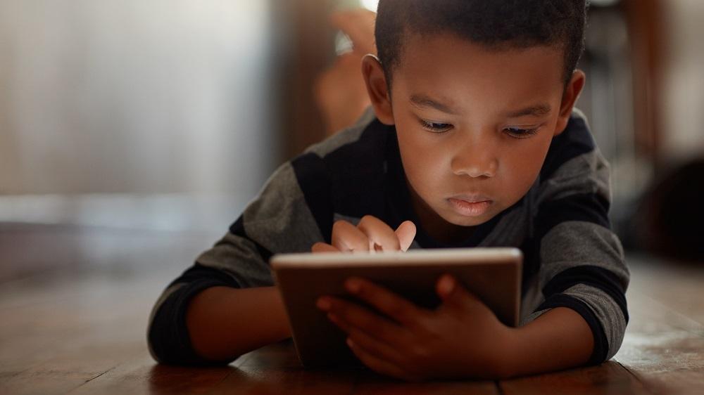 Child laying on floor with tablet computer