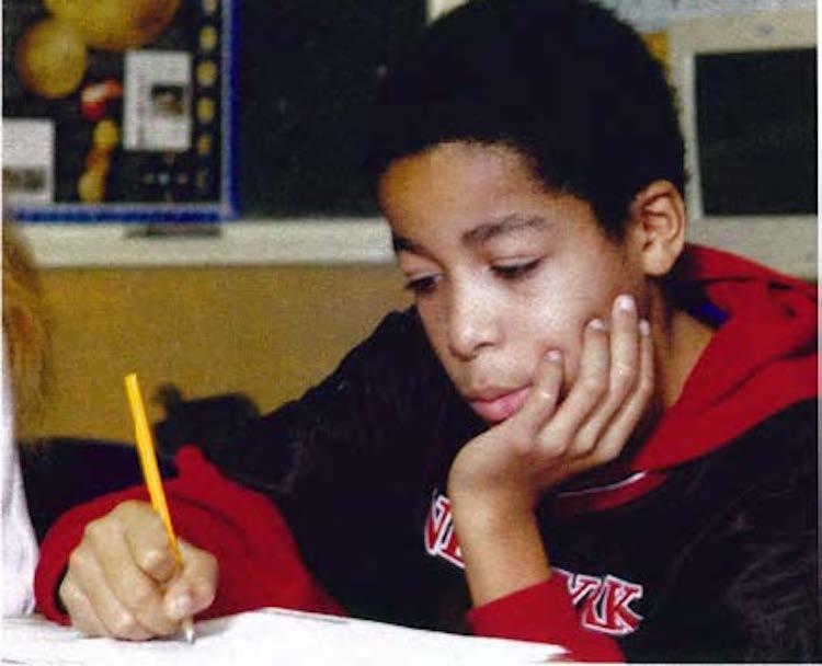 child in classroom looking at workbook