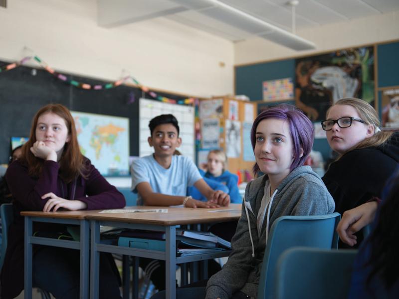 Students sitting at large desks in classroom