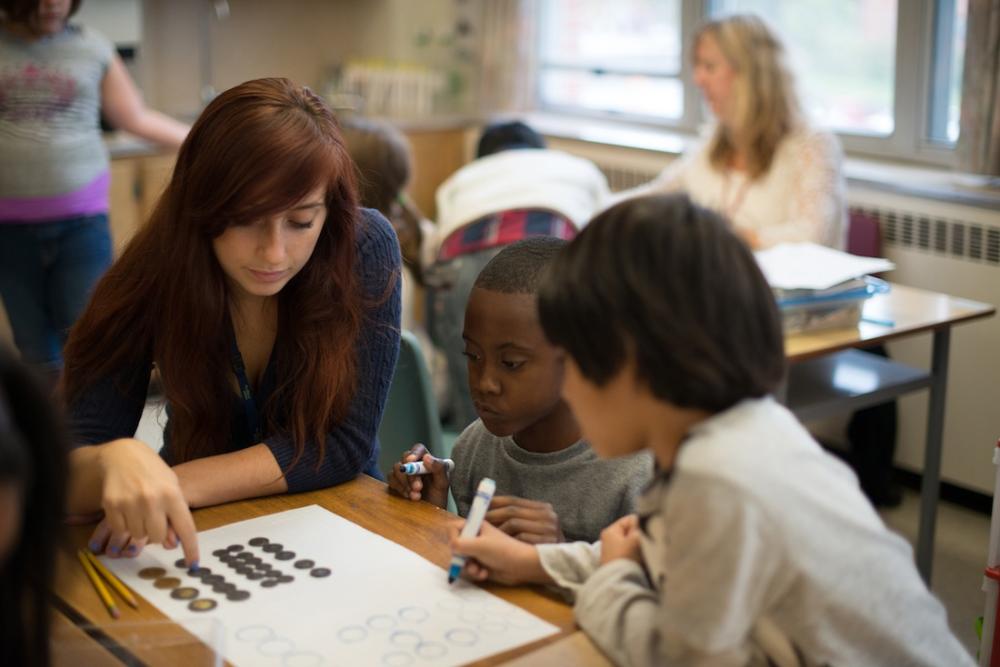 Teacher working with elementary student at table