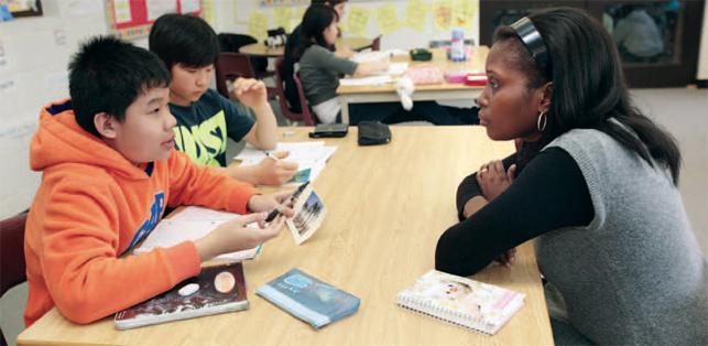 two students sitting at desk with teacher