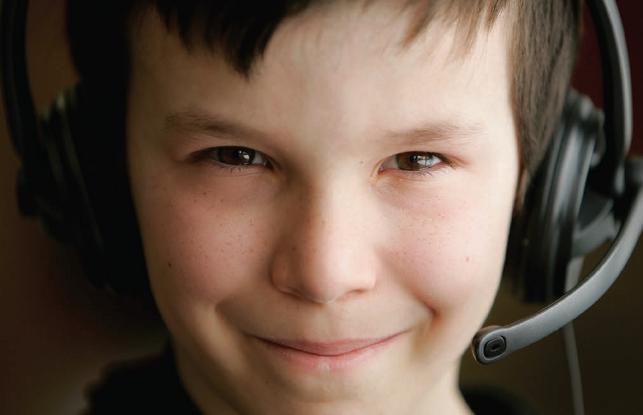 young boy with computer headset smiling looking at camera