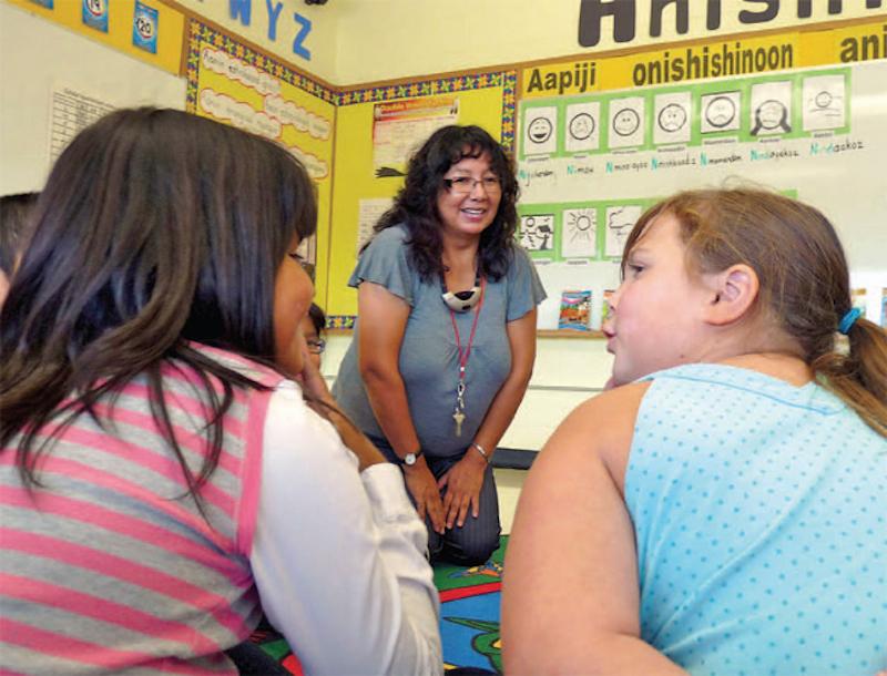 photo of two students sitting in front of teacher (perspective from behind students)