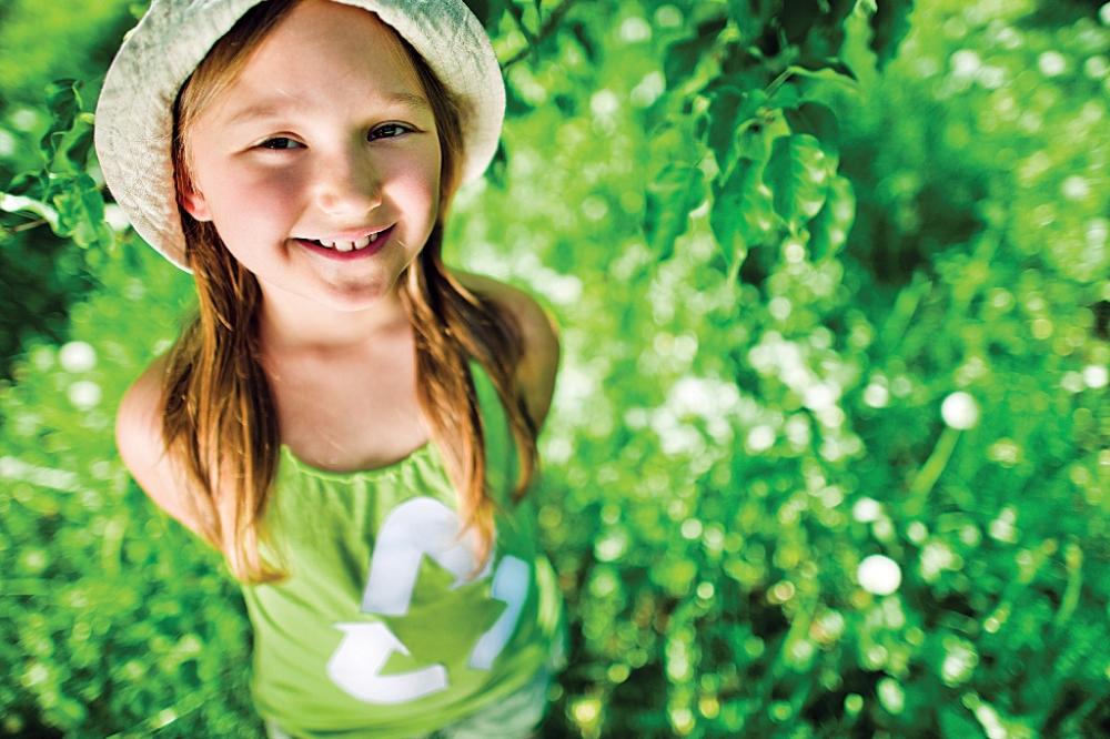 Young girl wearing green recycle shirt in field of grass