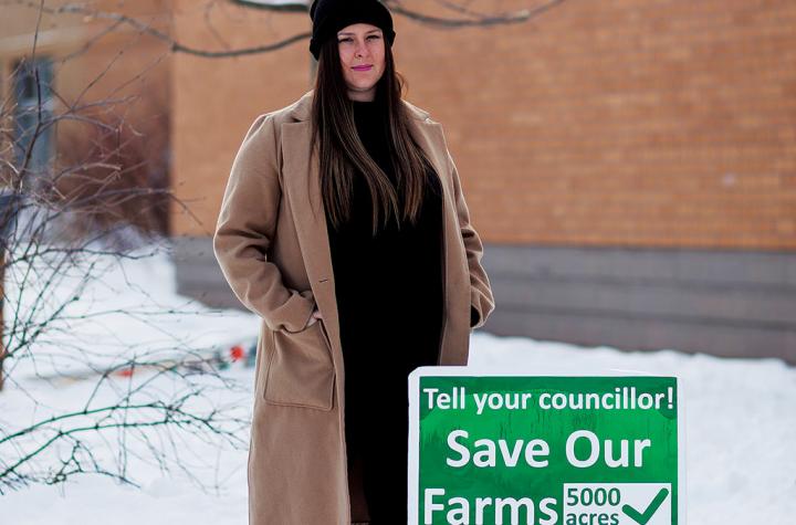 Sarah Lowes standing next to sign for saving farms