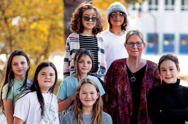 Teacher and girls standing in front of school