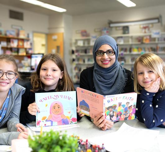 Teacher and students in classroom holding books