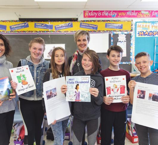 students and teachers holding books and articles