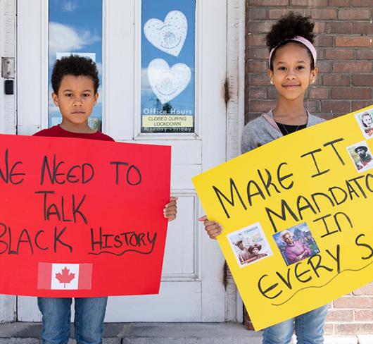 Children standing outside of school holding Black History posters they made