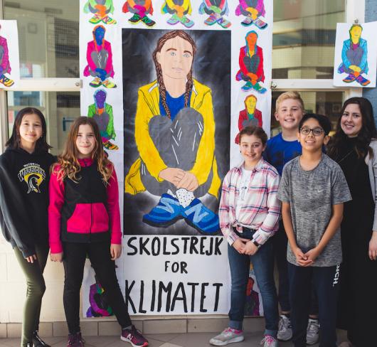 class and teacher standing in front of artwork