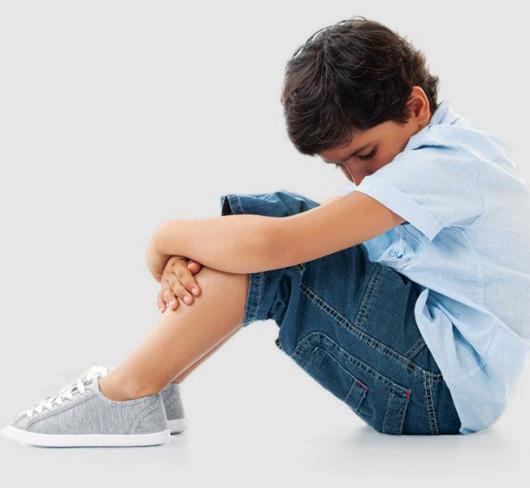 young boy sitting with head in lap