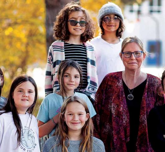 Teacher and girls standing in front of school