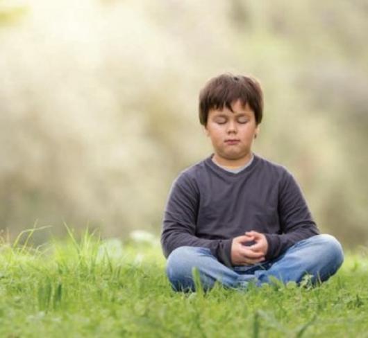 Young boy meditating in the park