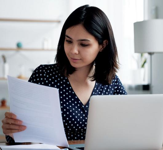 Woman sitting at laptop examining document