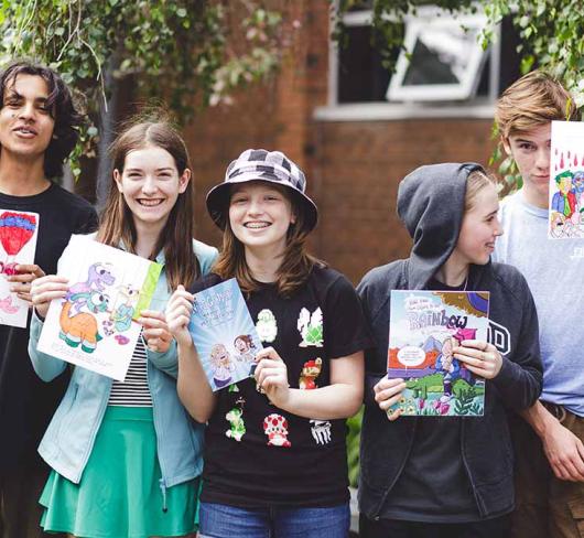 Students standing outside of school holding up school project