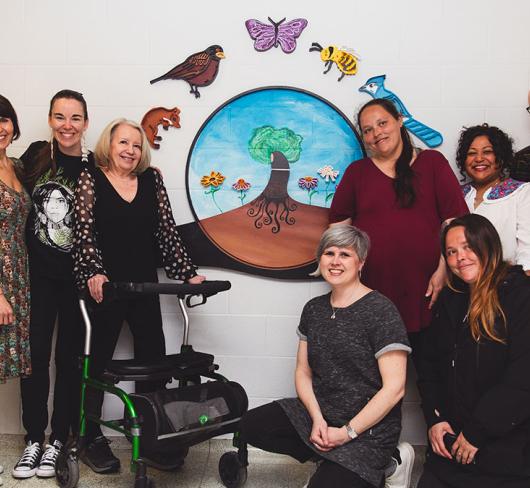 Staff posing in front of mural