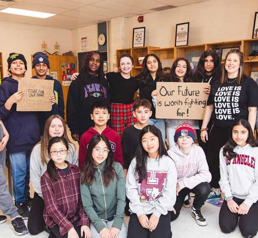 Students in classroom holding signs that promote activism