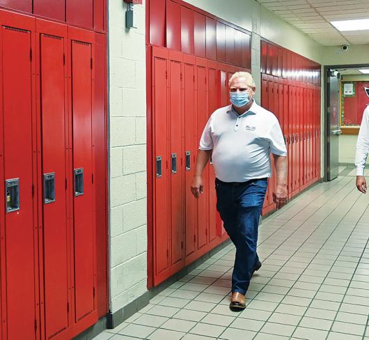 Doug Ford and Stephen Lecce walking down hallway with red lockers