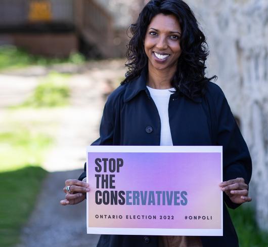 Cindy Gangaram holding "Stop the Conservatives" sign outside