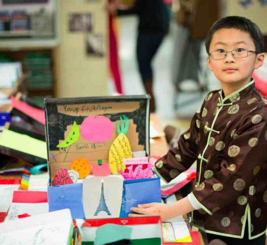 student standing next to diorama in classroom