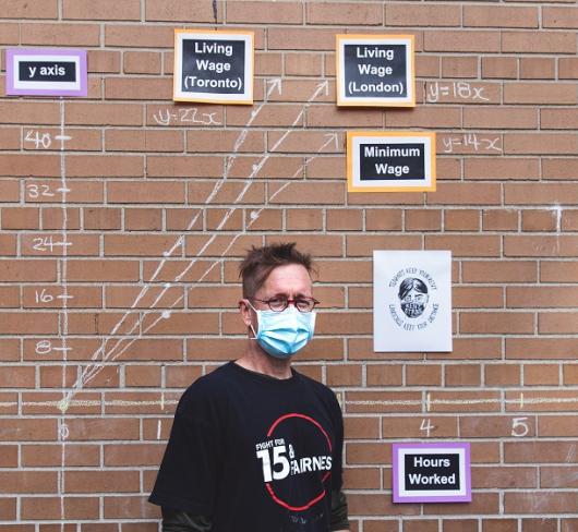 David Stocker standing in front of student project on wall outside of school