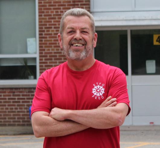 Sam Hammond posing outside of school in red ETFO t-shirt