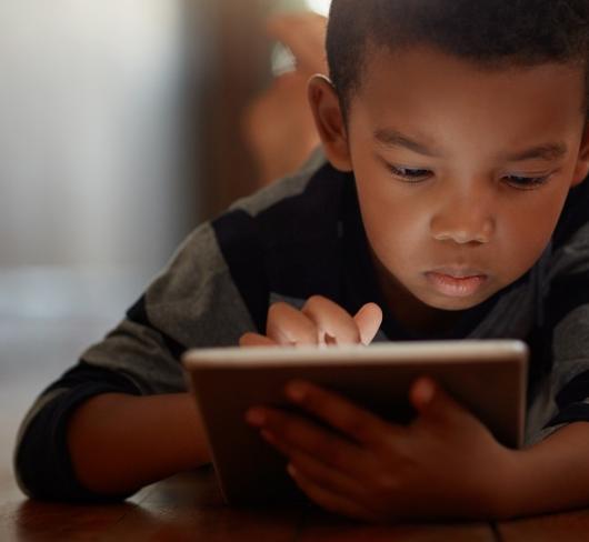 Child laying on floor with tablet computer