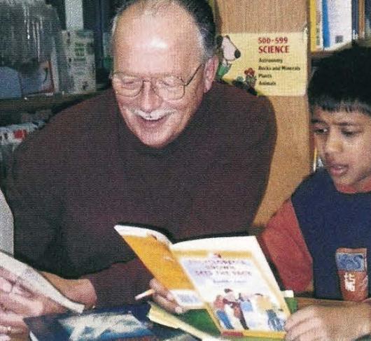 teacher reading with student in library