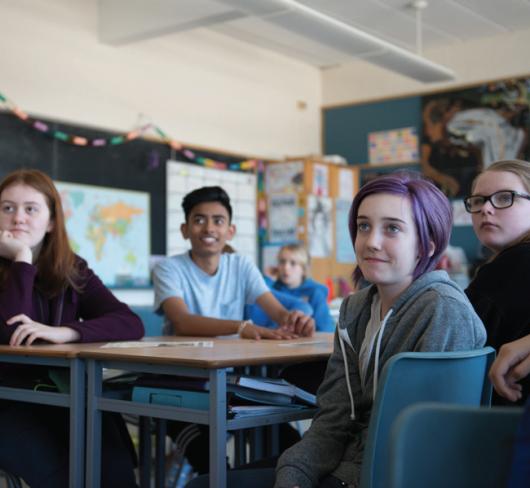 Students sitting at large desks in classroom