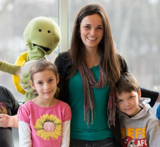 elementary students standing with teacher and puppet