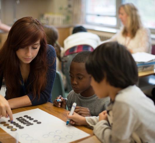 Teacher working with elementary student at table